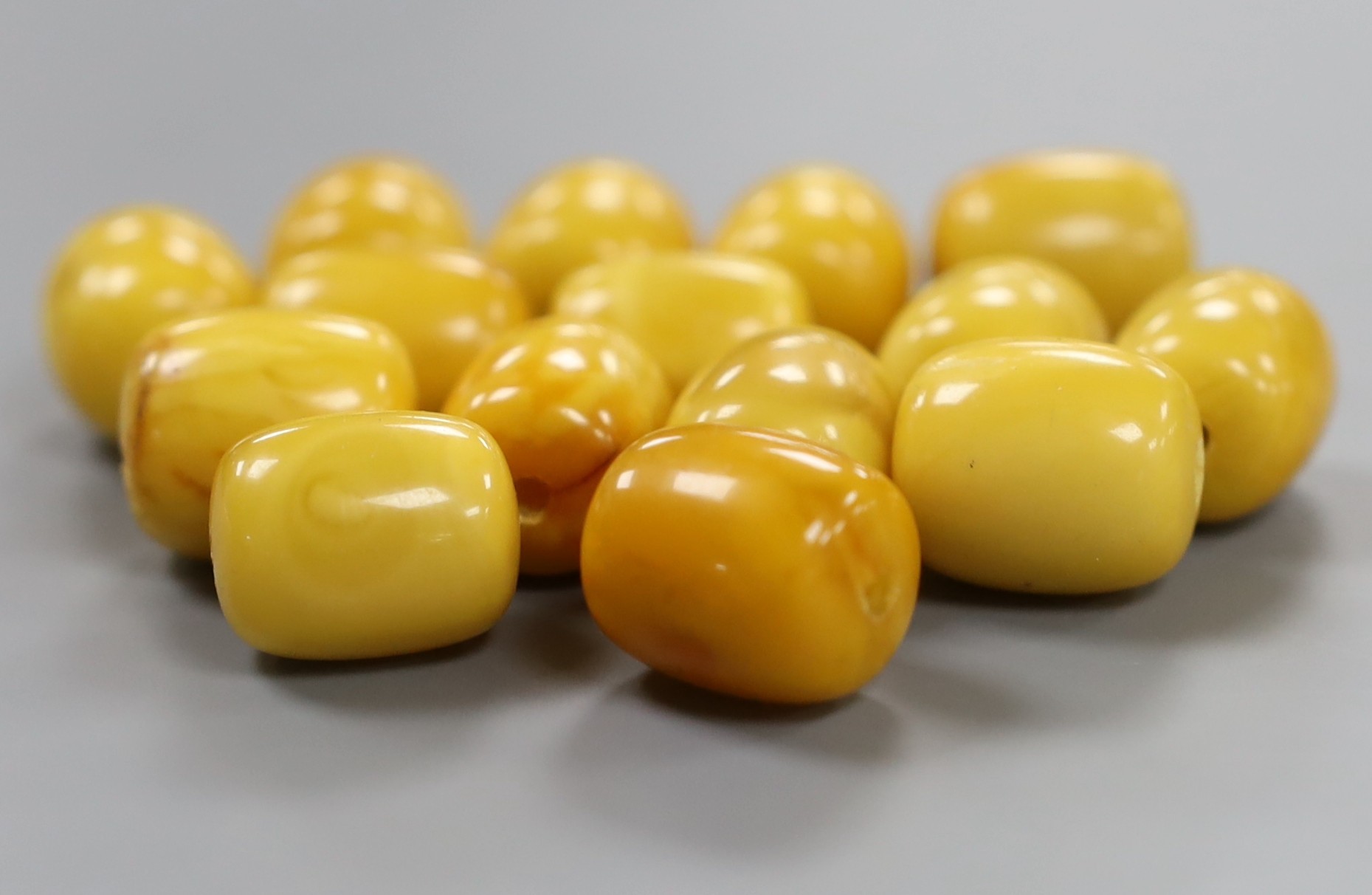 A group of fifteen loose drilled amber beads, 46 grams.
